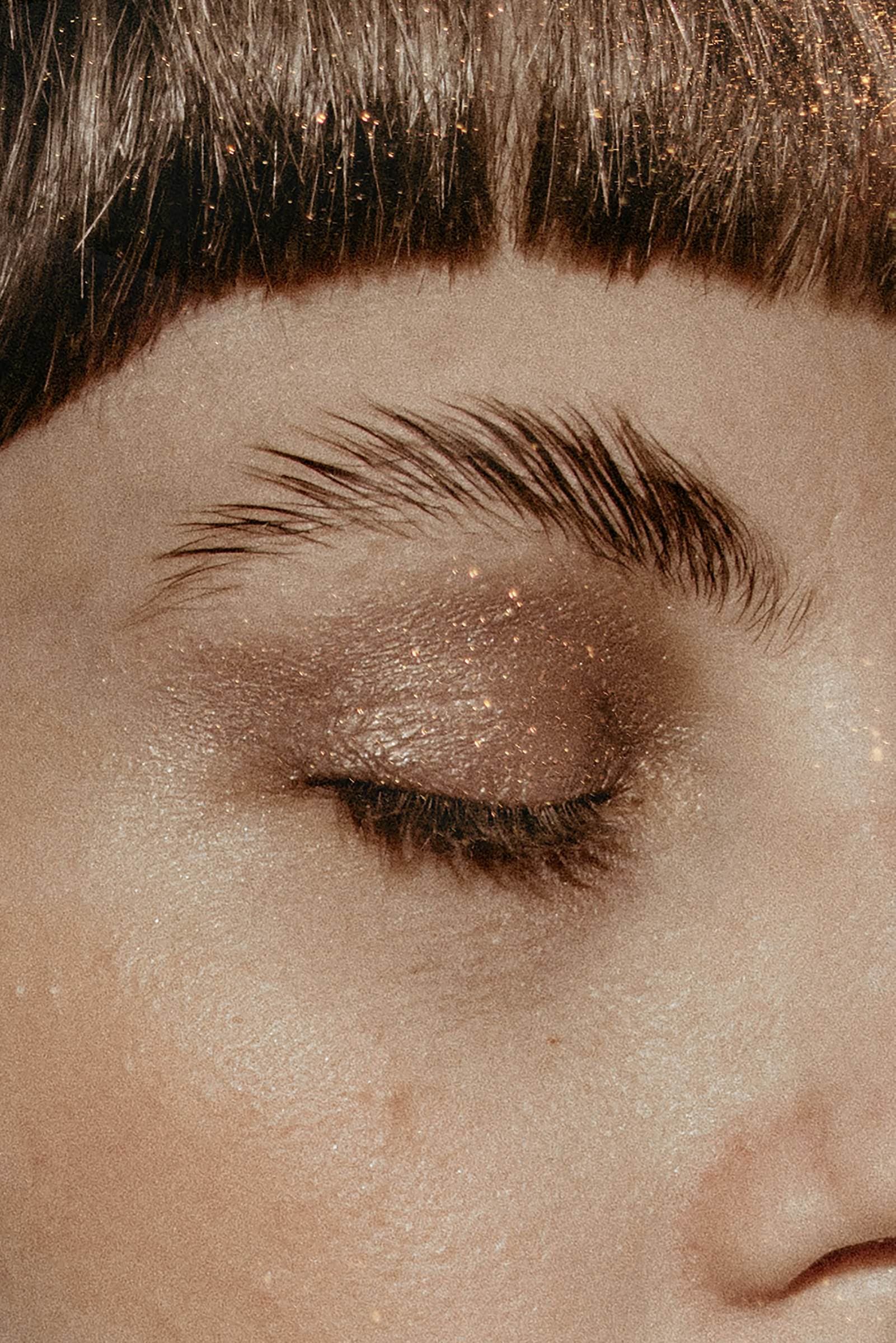Œil fermé et sourcil délicatement redessiné sur une peau dorée
