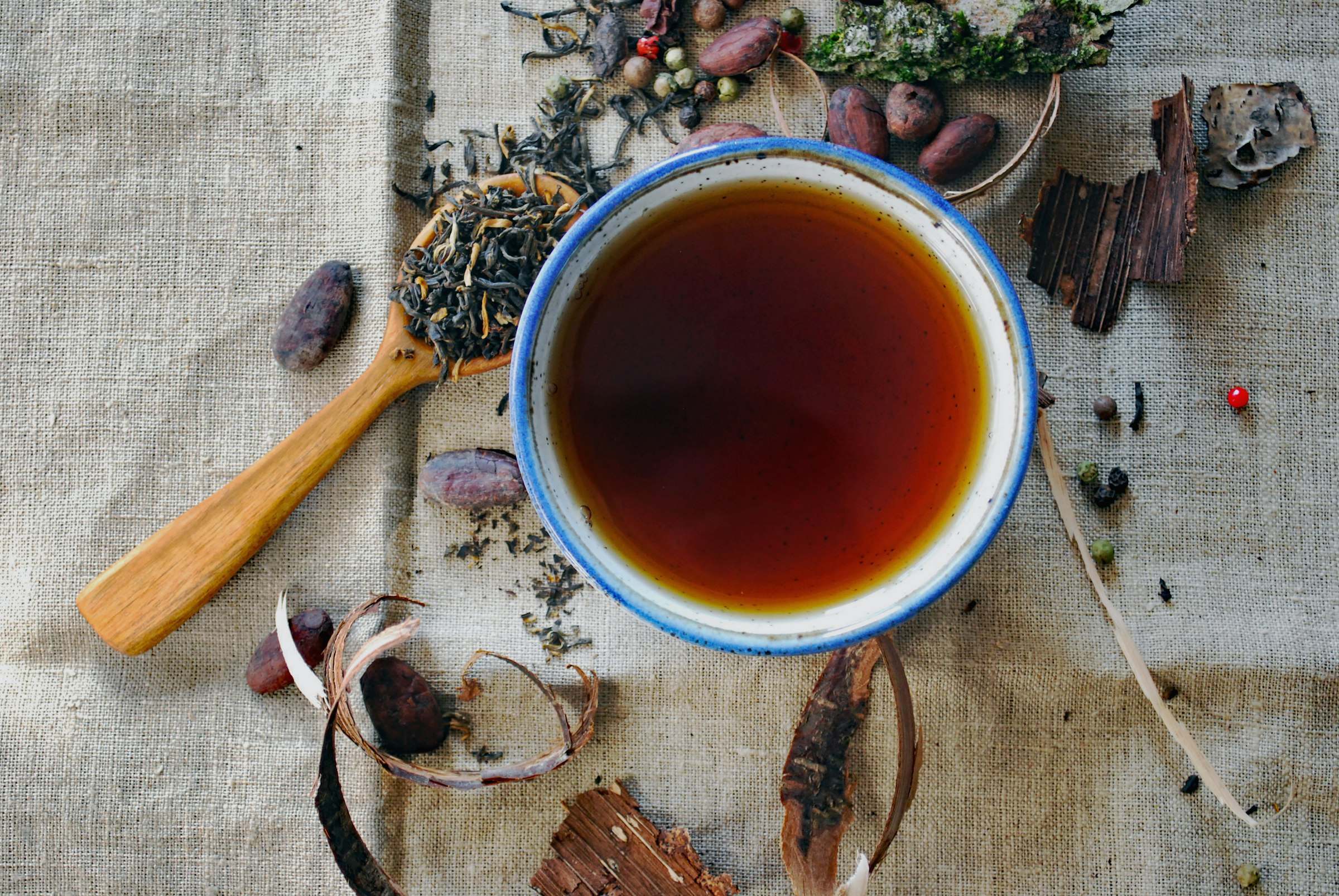 Tasse de tisane entourée d'herbes séchées et d'épices sur du lin